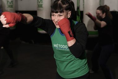 Energetic woman practicing boxing in a Buenos Aires gym with classmates.